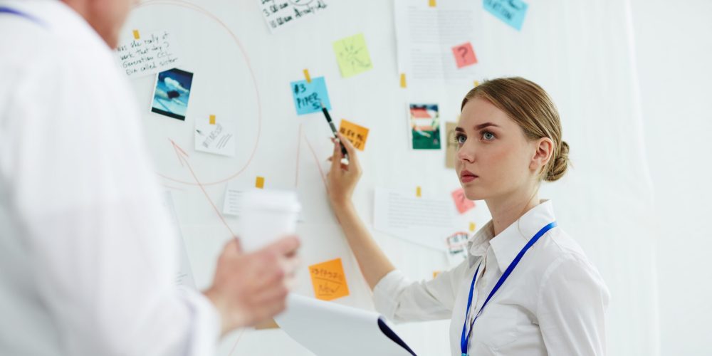 Young specialist consulting with her experienced colleague while pointing at one of evidence of crime on board