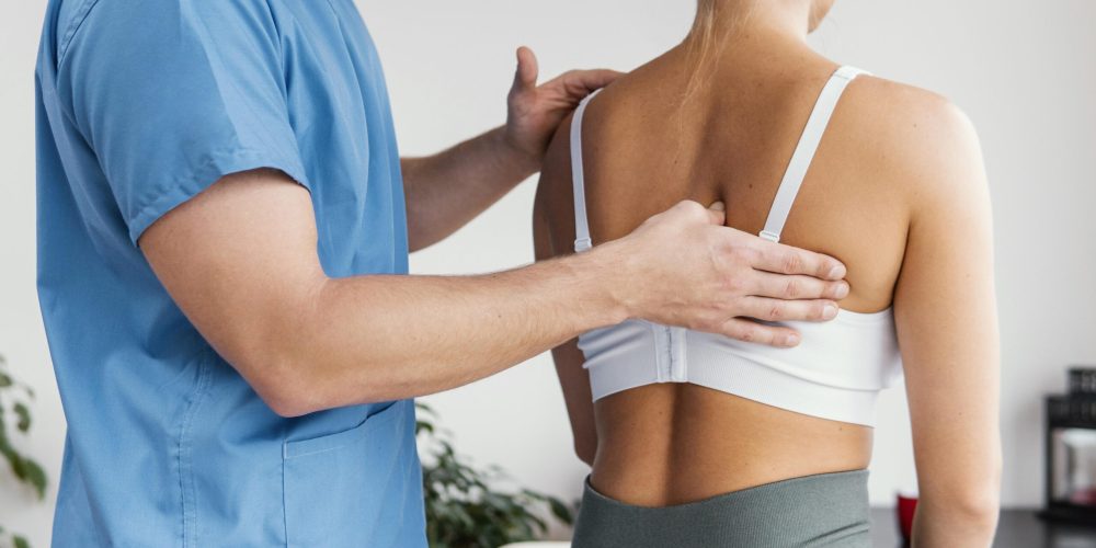 vista-lateral-terapeuta-osteopatico-masculino-comprobando-hueso-escapula-paciente-femenino